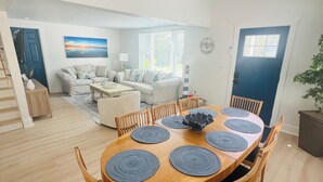 Un coin repas avec une table ronde en bois, six chaises et des sets de table bleus.