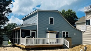 Une maison située en bord de mer, dotée d’un porche couvert, d’une petite terrasse et d’un garage visible.