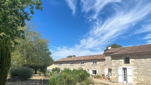 A stone building with a courtyard, featuring a garden with various plants and a small tree. - Large family home with swimming pool for 10 people (Puisseguin)