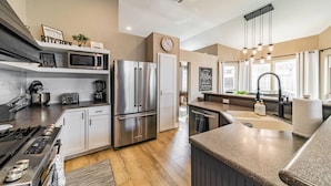 A modern kitchen with stainless steel appliances, a microwave, a clock, and a sink with a faucet.