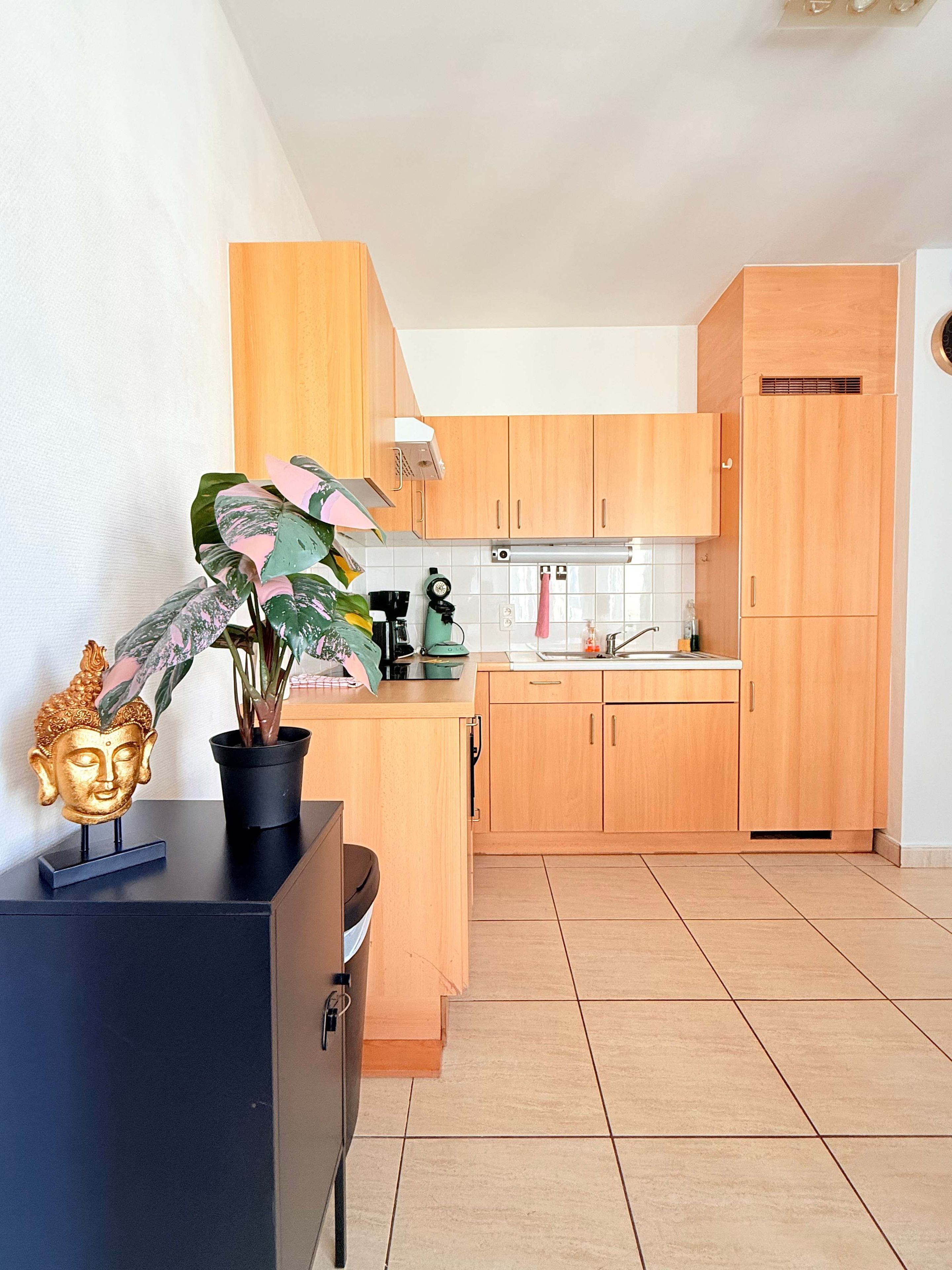 Een kleine keuken met houten kastjes, een spoelbak en een aanrecht.