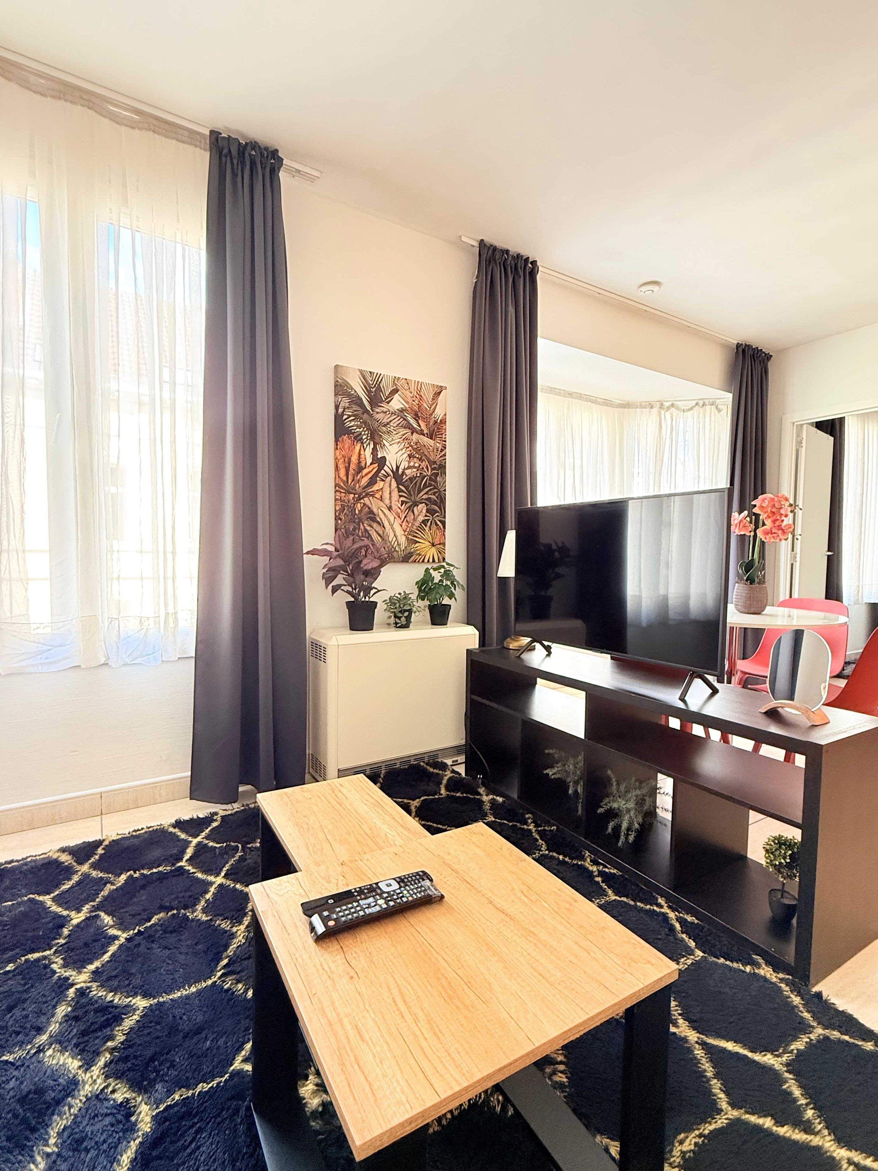 Une chambre d’hôtel dotée d’un grand téléviseur à écran plat, d’une table en bois, d’un canapé et d’une petite table basse.