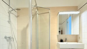 Un bagno moderno con cabina doccia in vetro, lavandino bianco e specchio.