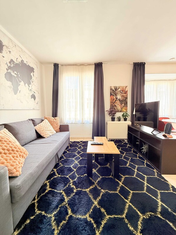A living room with a sofa, a coffee table, a TV, and a world map on the wall.
