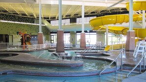 Um parque aquático interno com várias piscinas, toboáguas e área de recreação.