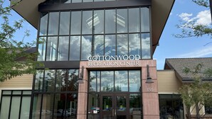 Um edifício moderno com grandes janelas de vidro e uma placa que diz 'Cottonwood Recreation Center'.