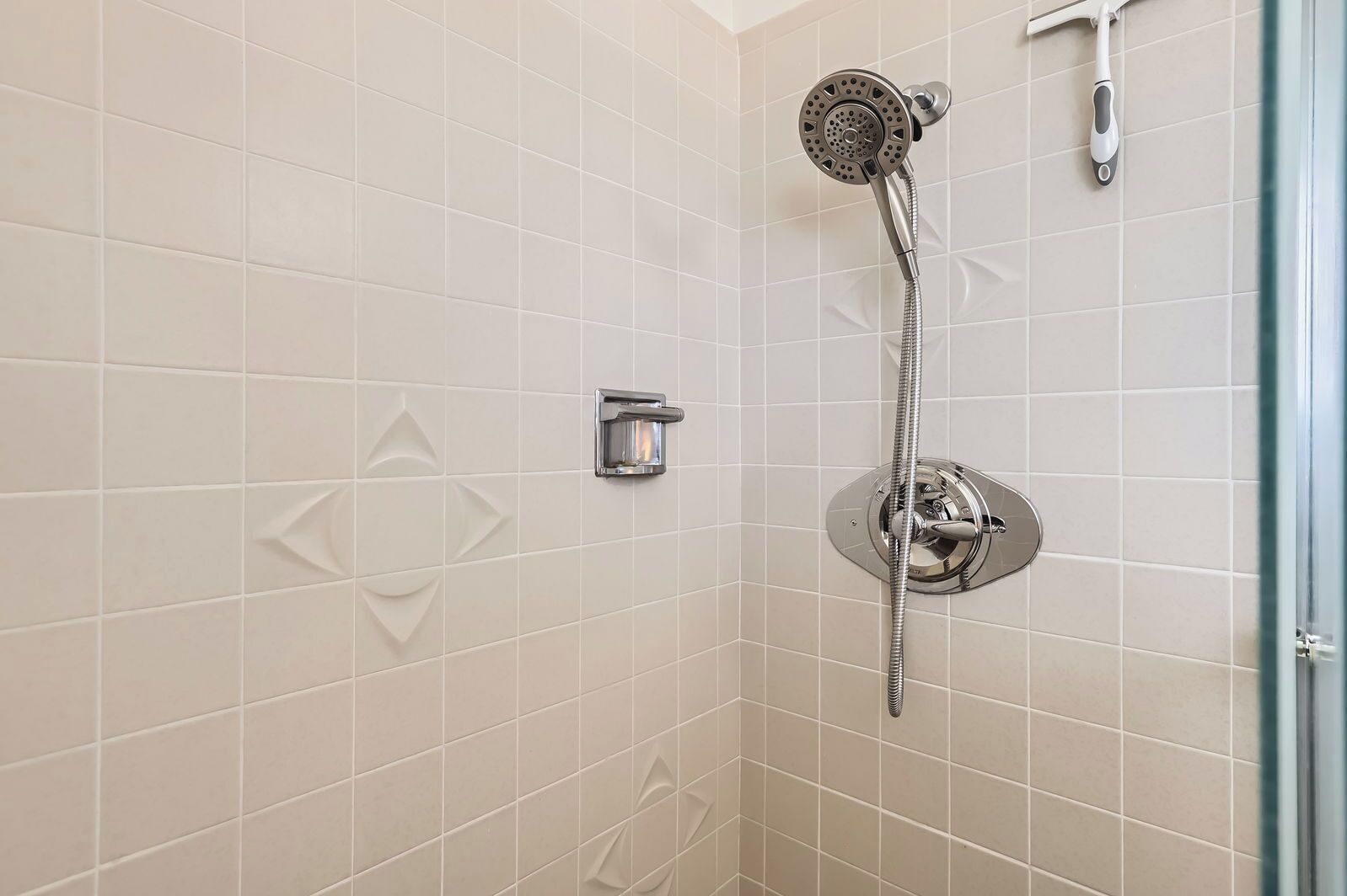 Une douche équipée d’un pommeau de douche à main et d’un robinet fixé au mur.