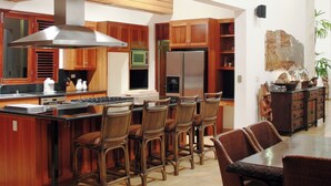 A spacious kitchen with a large island, wooden cabinets, and a dining area with chairs.