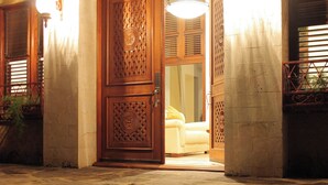 A stone building entrance with a wooden door and steps leading up to it.
