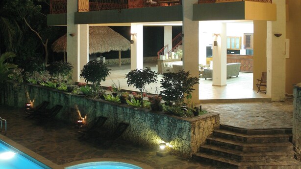 A two-story building with a pool, outdoor seating, and a well-lit entrance.