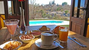 Una mesa de desayuno con vista a una piscina y colinas.