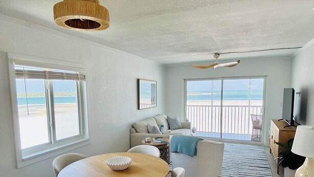 A spacious living area with a balcony, a dining table, and a TV.