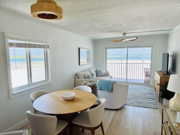 A spacious living area with a balcony, a dining table, and a TV.