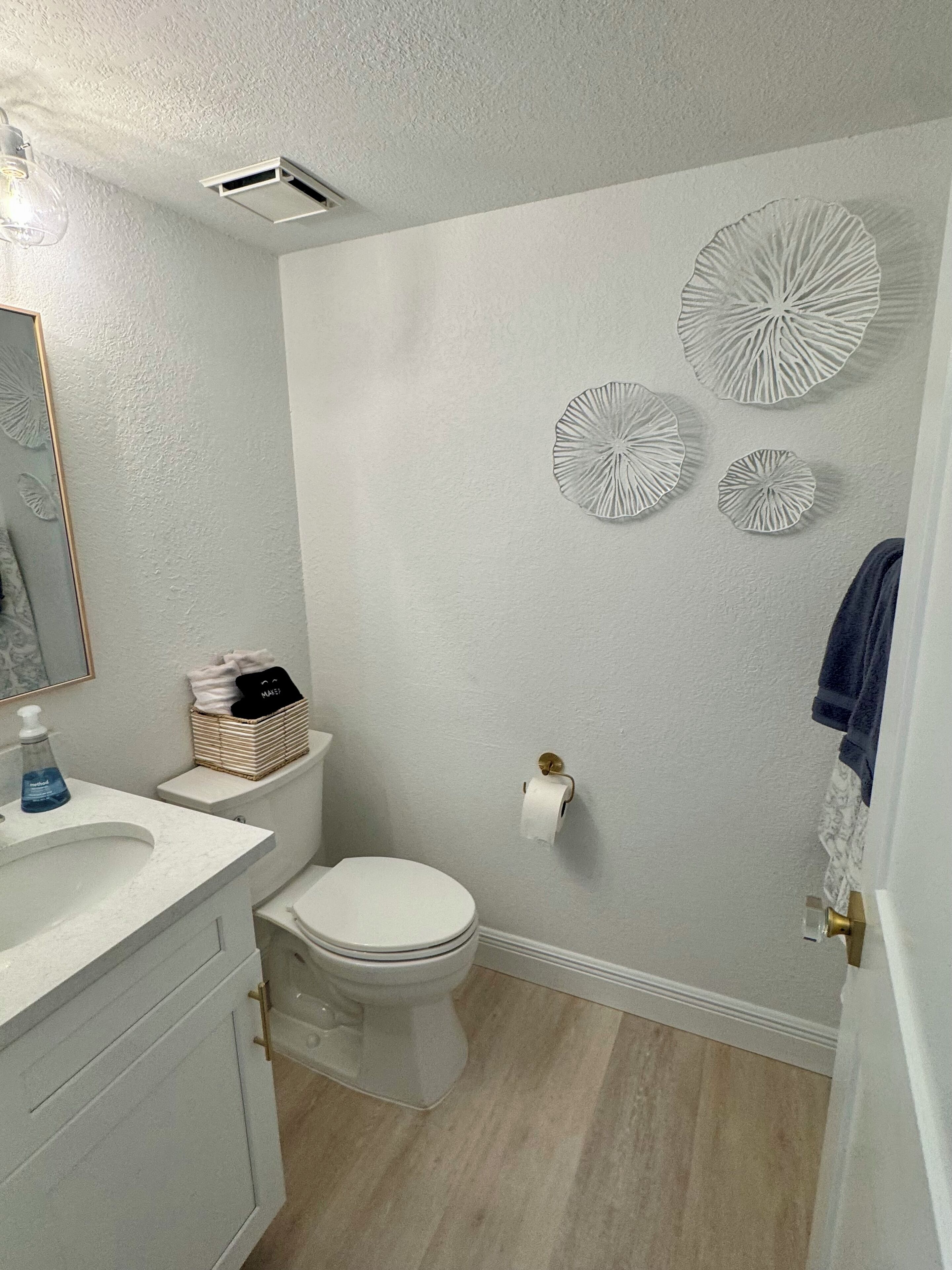 A bathroom with a toilet, sink, and decorative wall art.