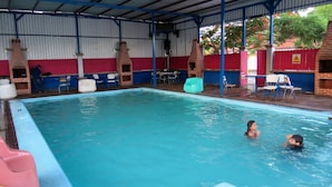 En swimmingpool med ett överbyggt område, stolar och en vattenrutschkana.