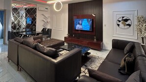 A modern living room with a sectional sofa, a flat-screen TV, and ambient lighting.