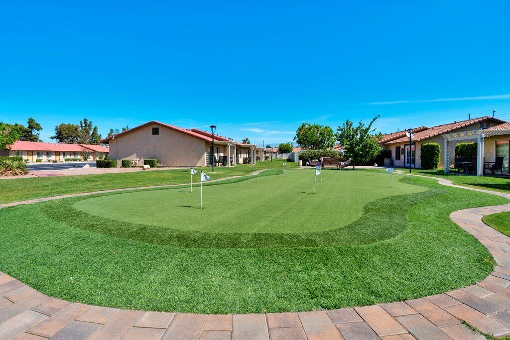 A well-maintained golf course with a clear path, surrounded by buildings with red-tiled roofs.