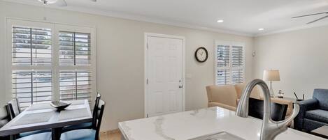 A modern kitchen with a marble countertop, stainless steel sink, and a ceiling fan.