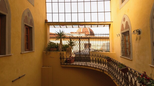 A yellow building with a glass ceiling, a balcony with plants, and a view of a dome in the background. - Elegant apartment with panoramic terrace in the historic heart of Pistoia (Pistoia)