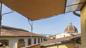A balcony with two wicker chairs, a table, and a view of a dome-topped building in the distance. - Elegant apartment with panoramic terrace in the historic heart of Pistoia (Pistoia)