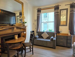 A living room with a television, sofa, and wooden furniture.