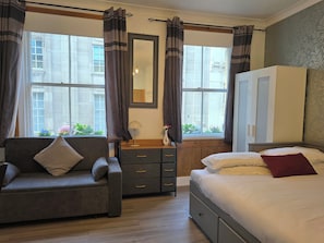 A bedroom with a sofa, a bed, a dresser, and a wardrobe.