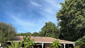 A house with a swimming pool, covered patio, and lush greenery. - Indonesian villa (Lacanau)