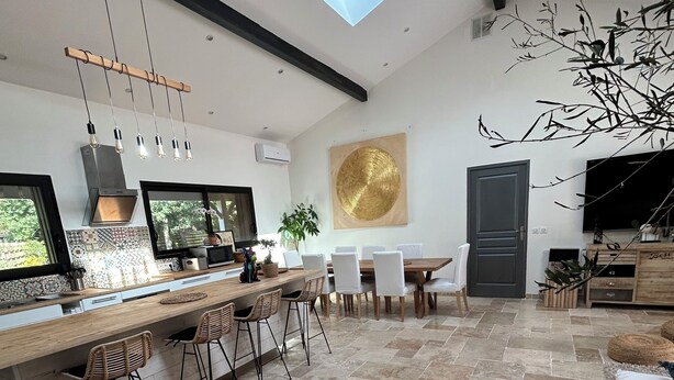 A modern kitchen with a bar area, dining space, and a large window. - Indonesian villa (Lacanau)