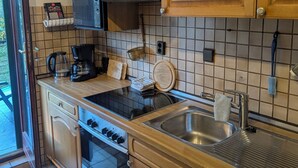 Una cocina con armarios de madera, estufa negra, fregadero y cafetera.