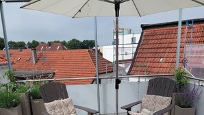 Ein Balkon mit zwei Stühlen, einem Tisch und einem Sonnenschirm.
