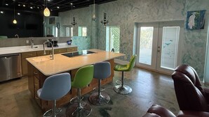 Moderni keittiö, jossa on keskeinen saareke, baarituolit ja ruokailutila.