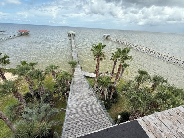 A wooden pier extending into a calm sea, with palm trees and a small structure at the end. - Charming 4-bedroom house close to Dauphin Island white sandy beaches (Coden)