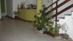 A reception area with a counter, potted plants, and a staircase. - Hotel Bahía Del Sol (San Clemente)