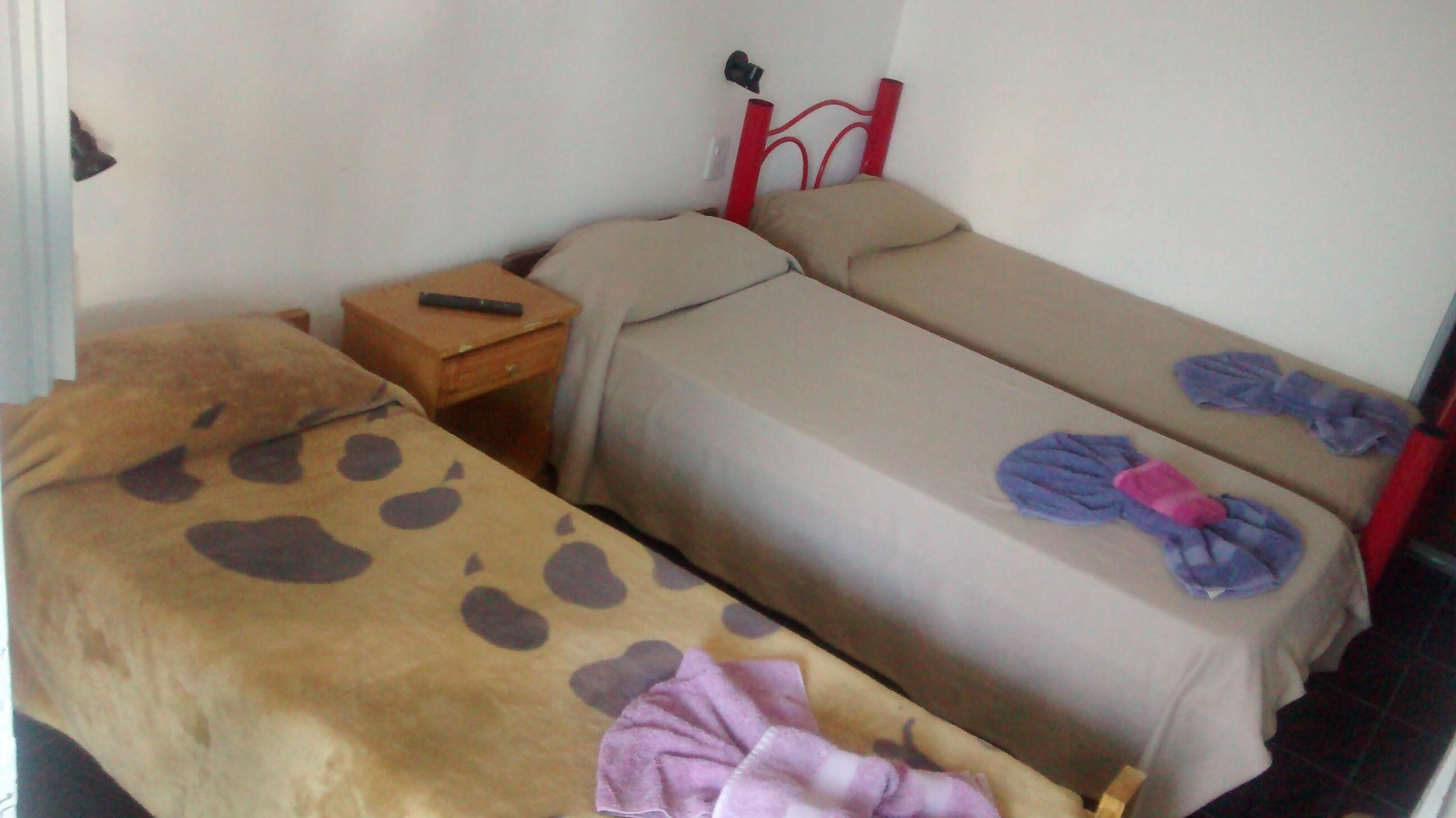 Un alojamiento pequeño y de una sola habitación, con cama, mesita de noche y cabecero de metal rojo.