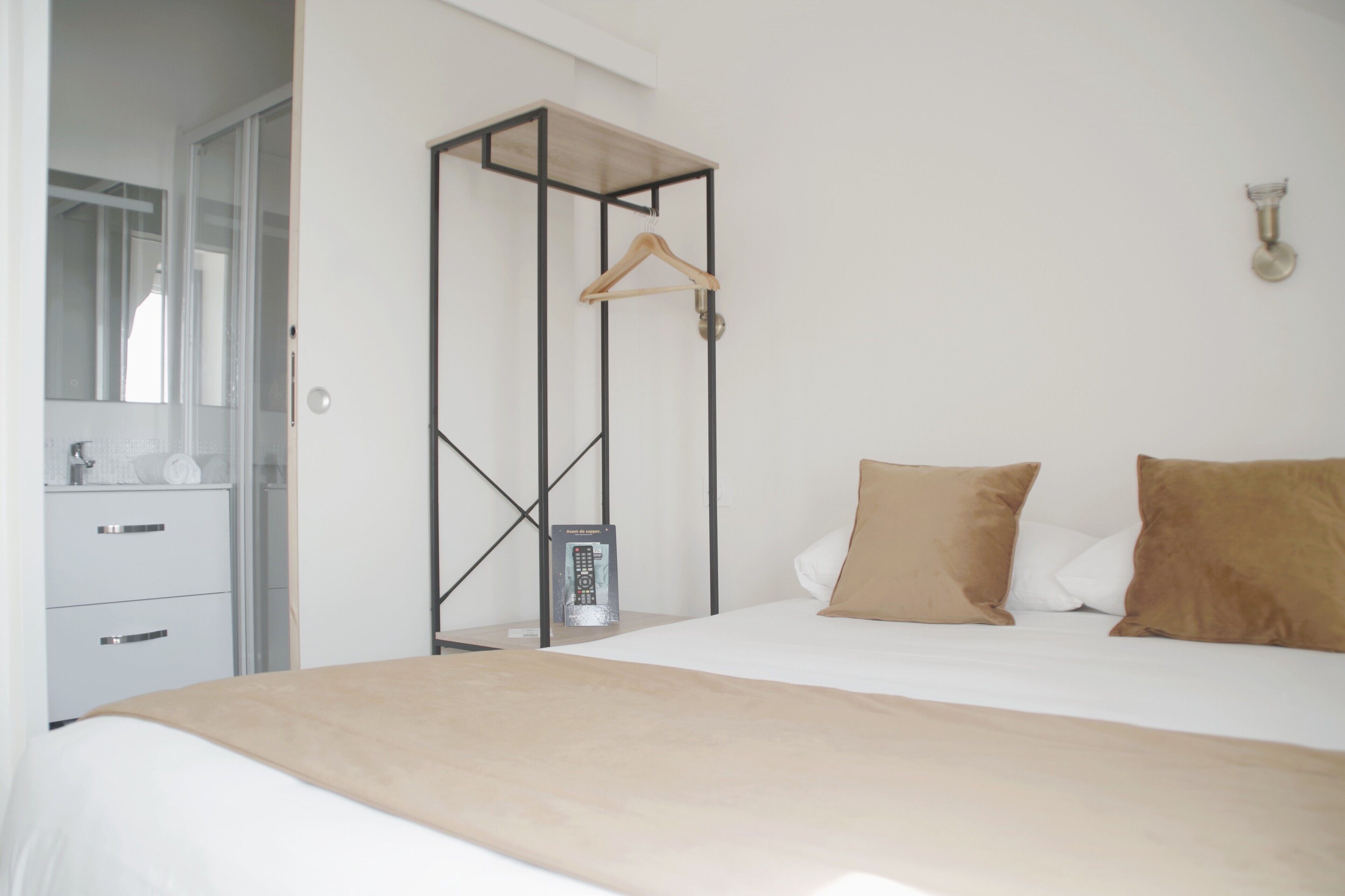 Ein Schlafzimmer mit einem Bett, einem Holzaufhänger, einem Kleiderschrank und einem Spiegel.
