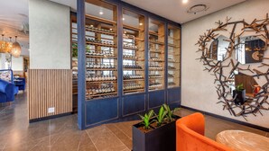 A modern hotel lobby with a wine cellar, a reception area, and a seating area with a decorative wall. - Where Convenience Meets Curated Luxury (Johannesburg)