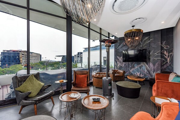 Un salón moderno con sillones de cuero, chimenea y grandes ventanales con vistas a la ciudad.