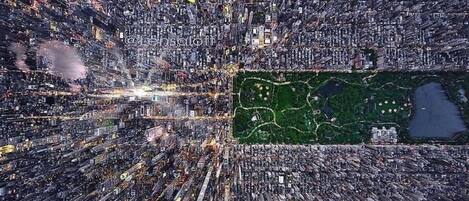 An aerial view of a densely packed urban area with a large green park in the center.