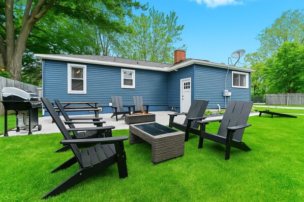 Una casa azul con patio, mobiliario exterior y una parrilla.