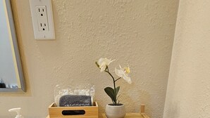 Un mueble de madera con un toalla, una planta en maceta y un recipiente de vidrio en un baño.