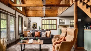 A spacious living area with a wooden ceiling, a sofa, a coffee table, and a chair.
