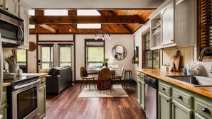 A kitchen with wooden beams, a dining area with a table and chairs, and a built-in dishwasher.