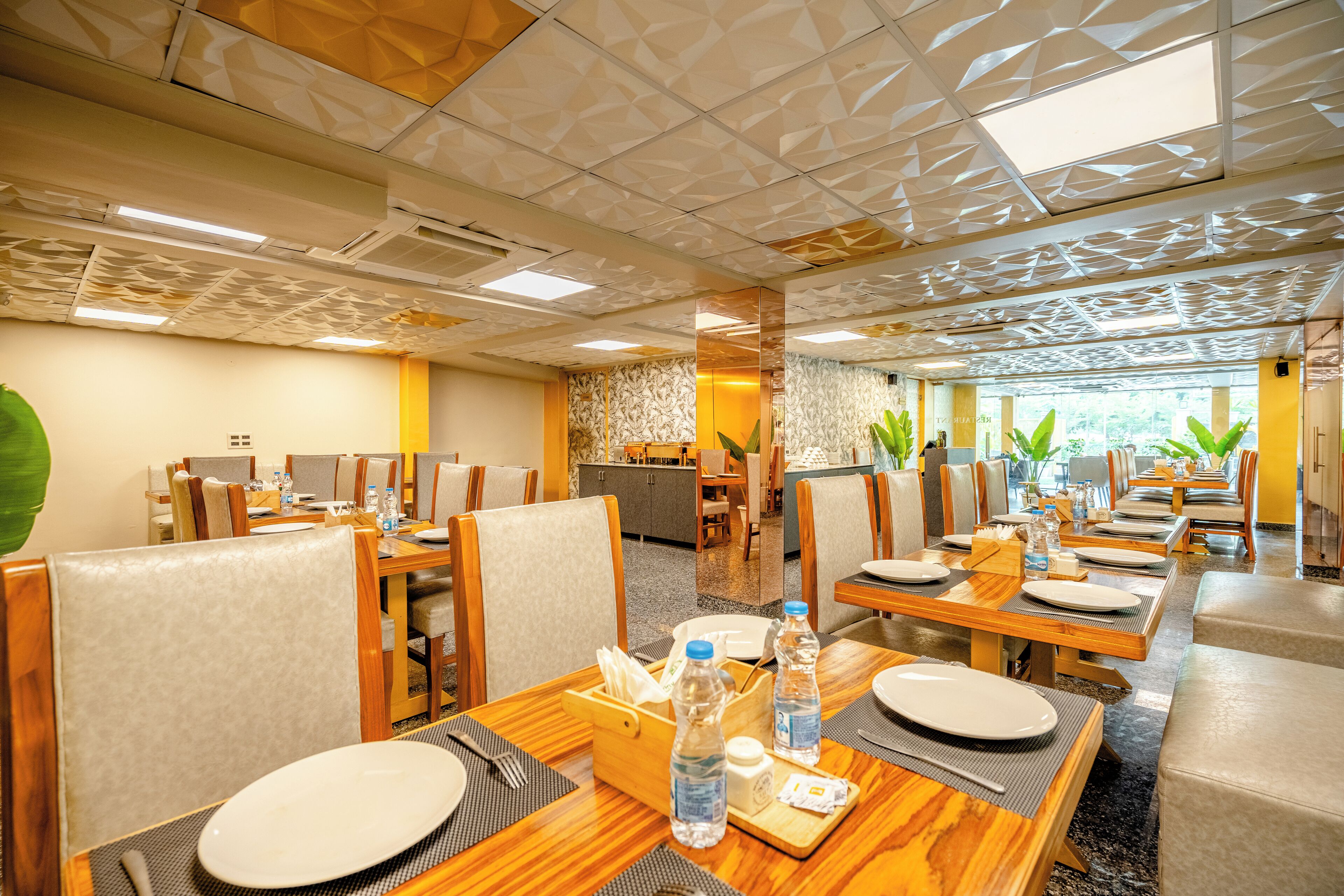 A hotel dining area with multiple tables and chairs, equipped with water bottles and place settings.
