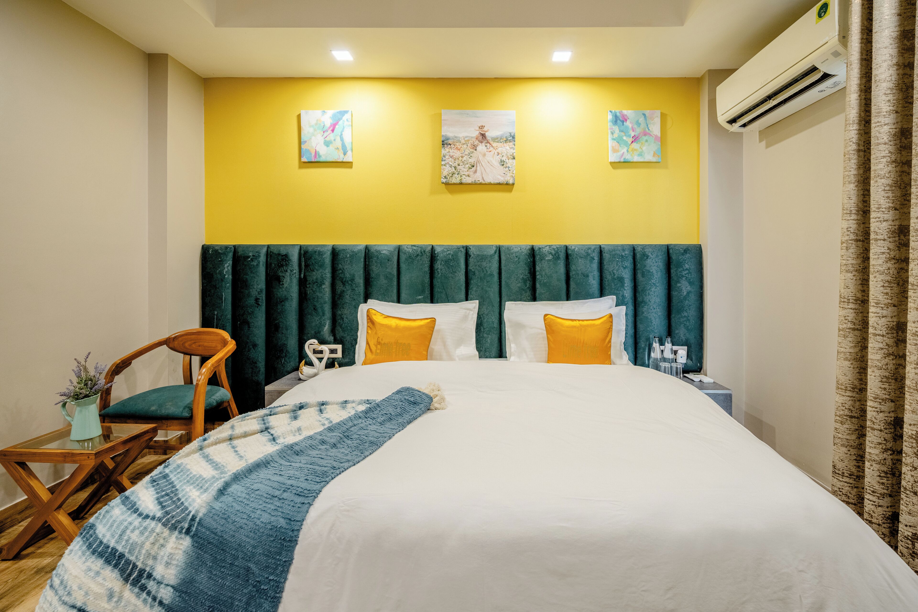 Habitació d'hotel amb un llit, una cadira, una taula petita i obra d'art a la paret.
