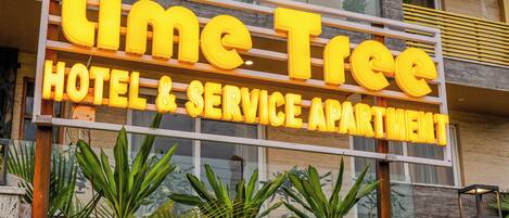 Señal de hotel con el nombre 'Lime Tree Hotel & Service Apartment'.