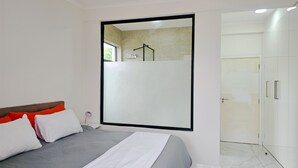 Et moderne soveværelse med en stor seng, et walk-in closet og et badeværelse med bruser.