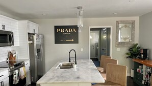 A modern kitchen with white cabinets, a marble island, and a black faucet.
