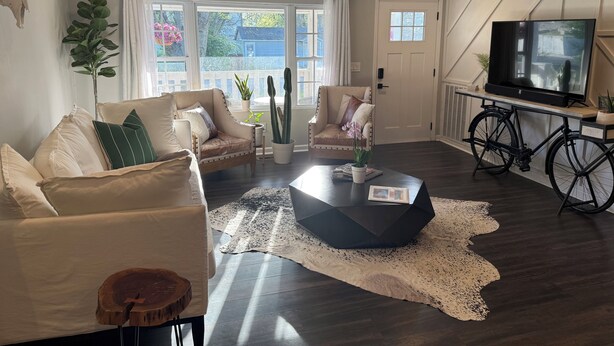 A living room with a sofa, armchairs, a coffee table, a TV, and a ceiling fan.