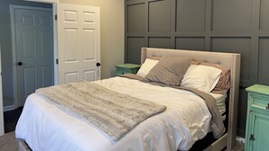 A bedroom with a bed, a nightstand, a door, and a ceiling fan.