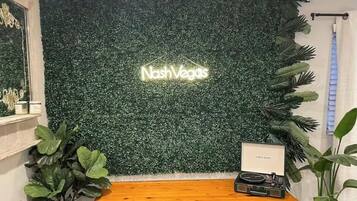 A reception desk with a neon sign reading "Nash Vegas" against a green foliage backdrop.